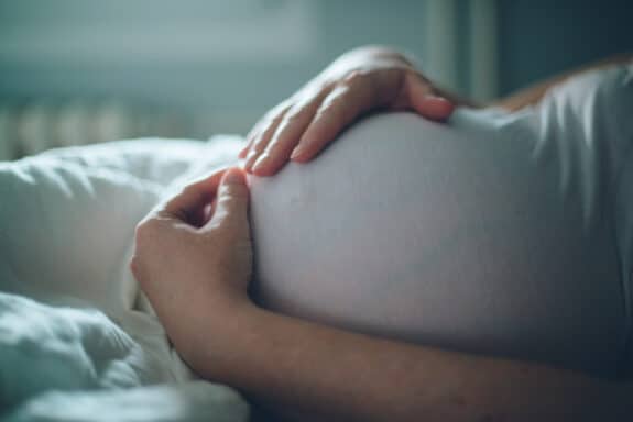 pregnant woman laying down hodling her growing belly