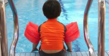 child sitting at the side of the pool