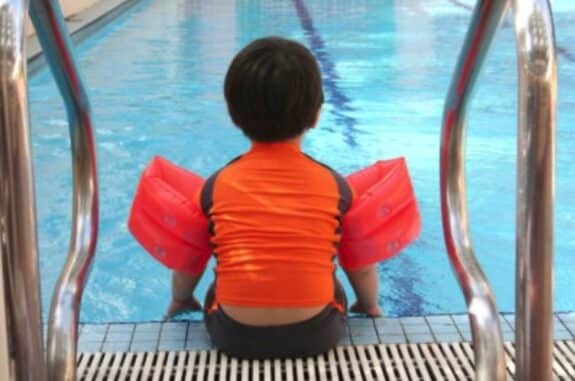 child sitting at the side of the pool