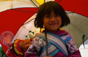 A young girl carries her sleeping baby brother on her back