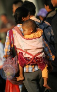 A mom carries her baby while heading to her ship at Xiuyinggang Port, China