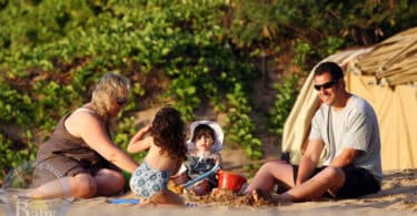 A nanny plays in the sand with Adam and daughters Sunny and Sadie