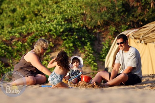 A nanny plays in the sand with Adam and daughters Sunny and Sadie