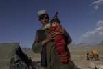 A Kuchi tribal man carries a six-month-old baby traditionally wrapped up