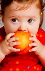 little girl eating a peach