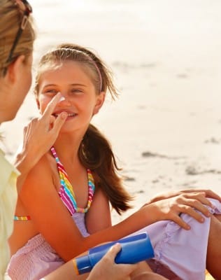 Mom putting sunscreen on daughter