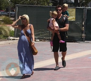 A pregnant Tori Spelling with Dean McDermott backpacking son Liam while carrying daughter Stella