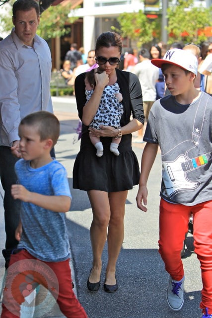 Victoria carries Harper while out shopping with Brooklyn and Cruz