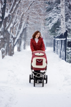 young mother with baby carriage snow