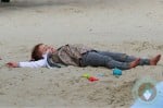 Honor Warren lays in the sand at the park