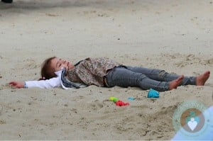 Honor Warren lays in the sand at the park