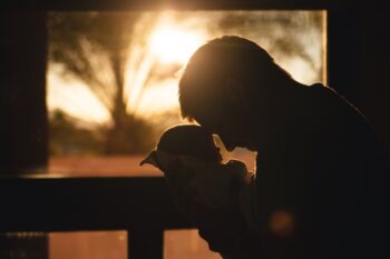 Man Carrying Baby Drawing Their Foreheads