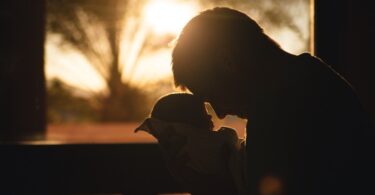 Man Carrying Baby Drawing Their Foreheads