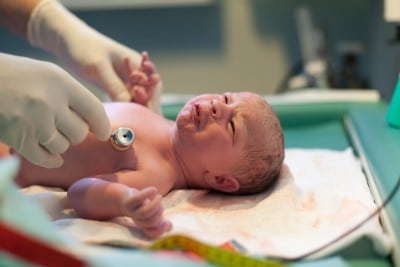 Newborn baby being examined in delivery room by doctor