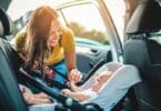 mom putting baby in car seat