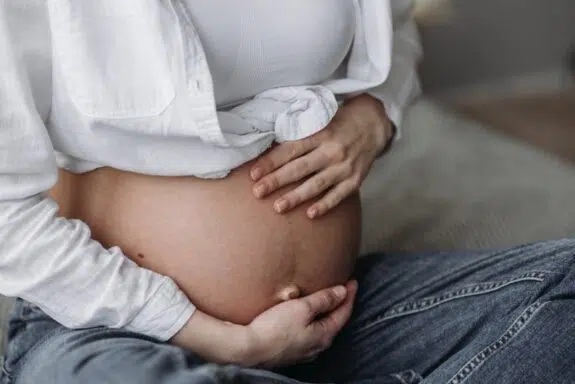 woman cradles her pregnant belly