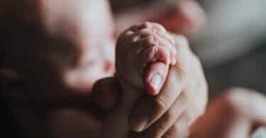 person holding newborn baby's hand