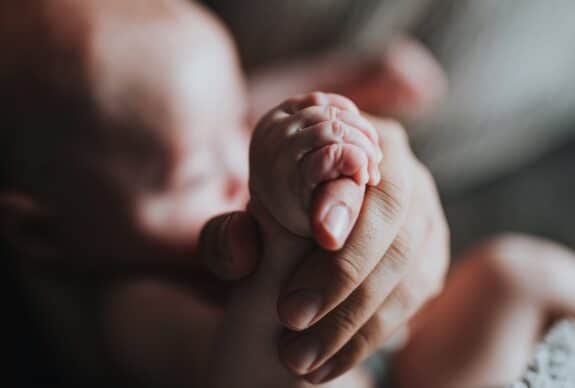 person holding newborn baby's hand