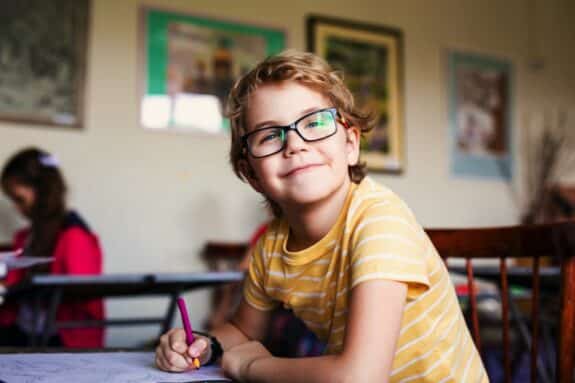 Blonde boy with glasses drawing