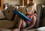 toddler sitting on a couch watching an ipad