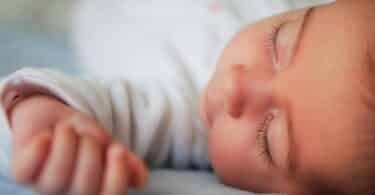 Newborn baby girl sleeping on blue sheets