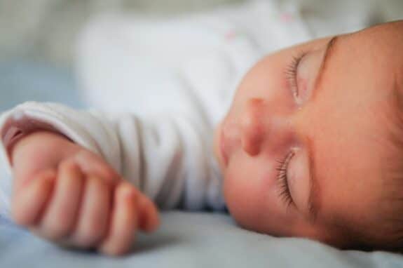 Newborn baby girl sleeping on blue sheets