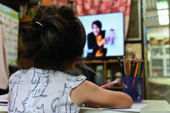 close up Schoolgirl learning online sitting on floor and watching television