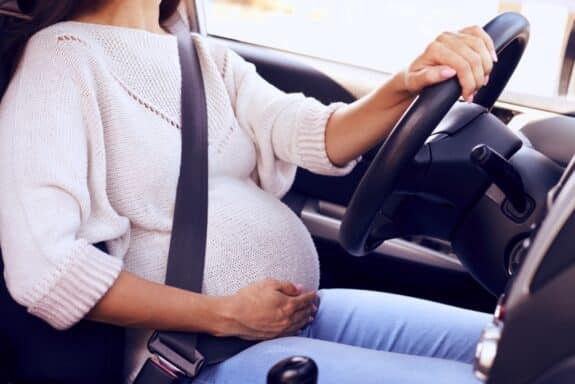 Fasten pregnant woman at wheel driving car