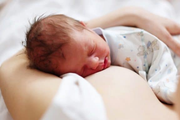 One day old newborn baby with mother