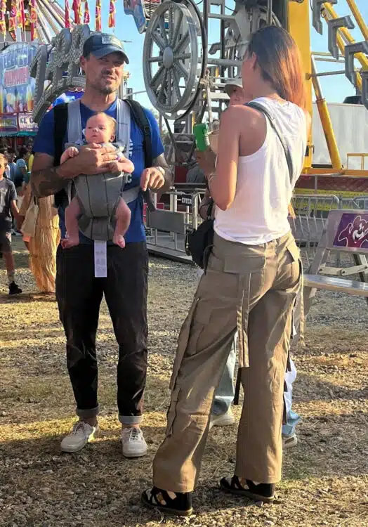 father standing with friends with his baby in a carrier