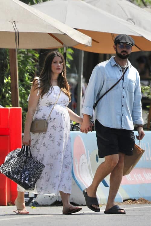 ashley green in a shite floral dress holds her husbands hand as they leave lunch in la