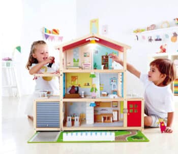 two kids playing with a wooden dollhouse