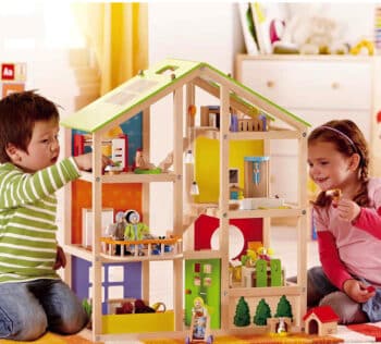 two kids playing with a wooden playhouse