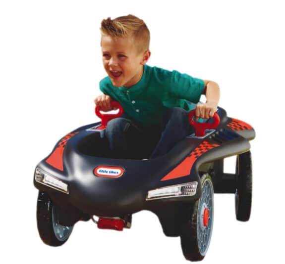 boy in a little tyke racing car with a smile on his face