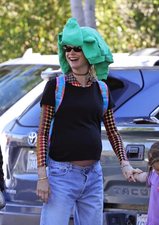 pregnant woman with backpack on and green sweater on her head