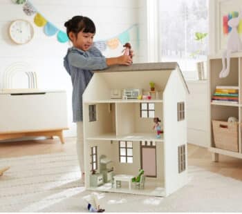 little girl playing in the back of her wooden dallhouse