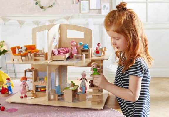 child playing with a wooden dollhouse