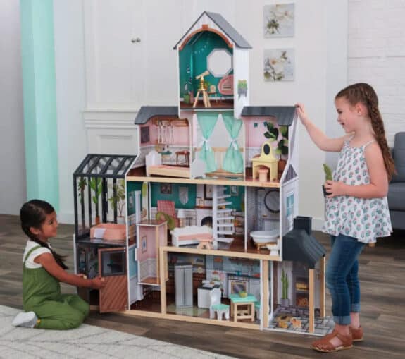 two kids playing with a wooden dollhouse