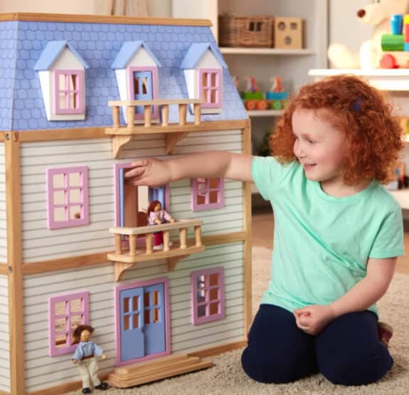 young girl playing with a dollhouse