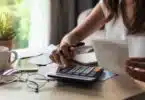 young woman checking bills, taxes, bank account balance and calculating expenses in the living room at home
