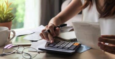 young woman checking bills, taxes, bank account balance and calculating expenses in the living room at home