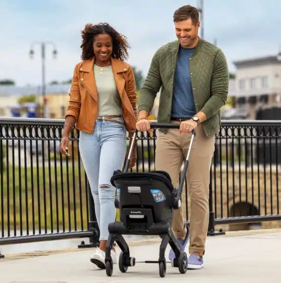 Parents pushing baby in Evenflo Shyft DualRide with Carryall Storage Infant Car Seat and Stroller Combo