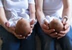 Infant twins being held by two parents