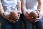 Infant twins being held by two parents