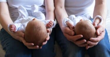 Infant twins being held by two parents