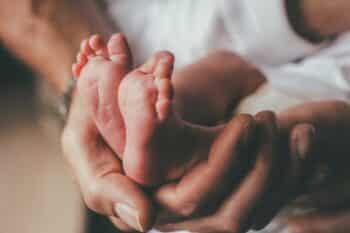 small feet of a newborn supported by the hand of his father