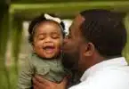 father kissing his baby daughter on the cheek