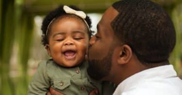 father kissing his baby daughter on the cheek