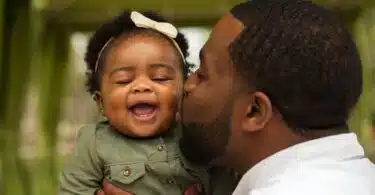father kissing his baby daughter on the cheek