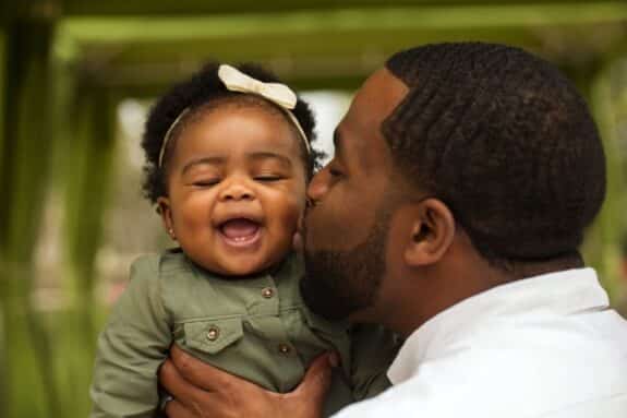 father kissing his baby daughter on the cheek